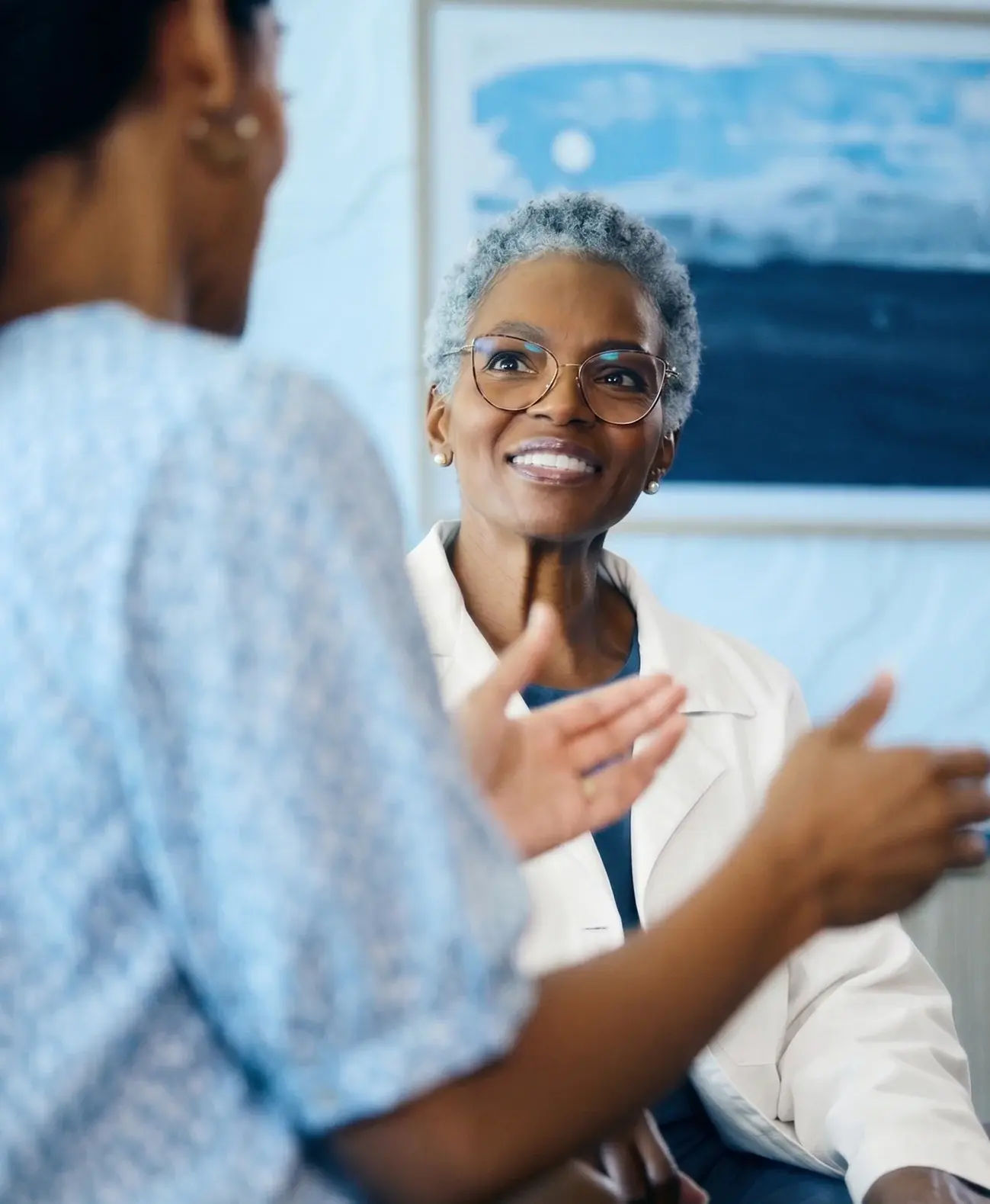 Physician in a white coat speaking with a patient during an office visit