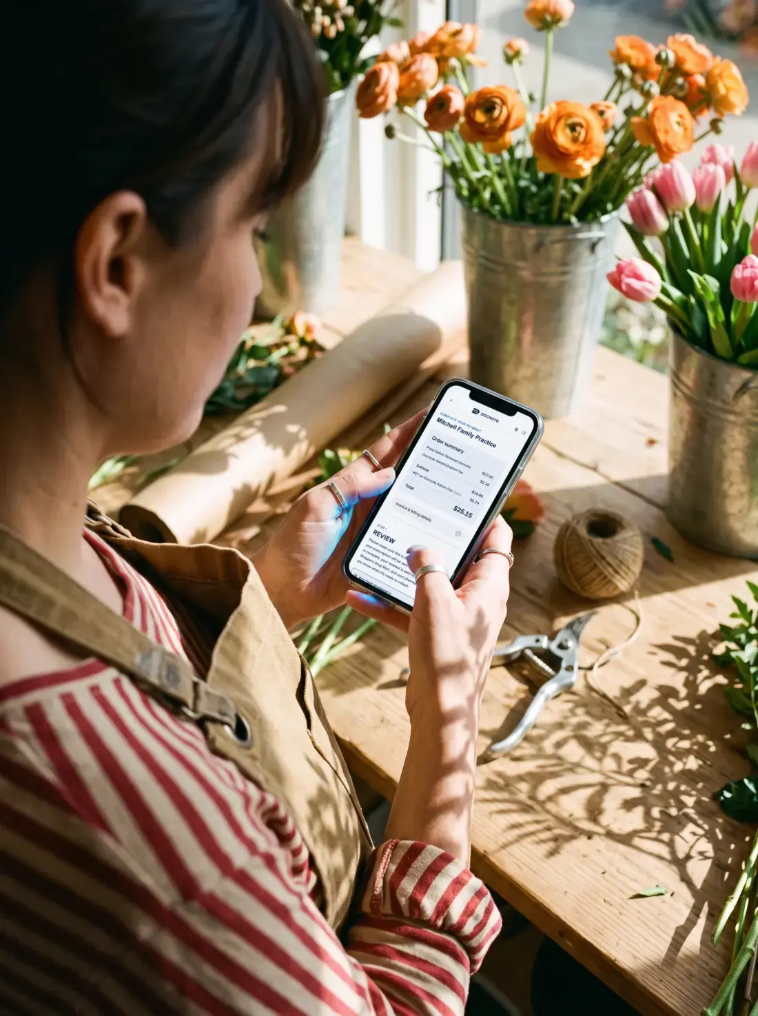 Florist checking a prescription renewal payment on her phone between bouquets